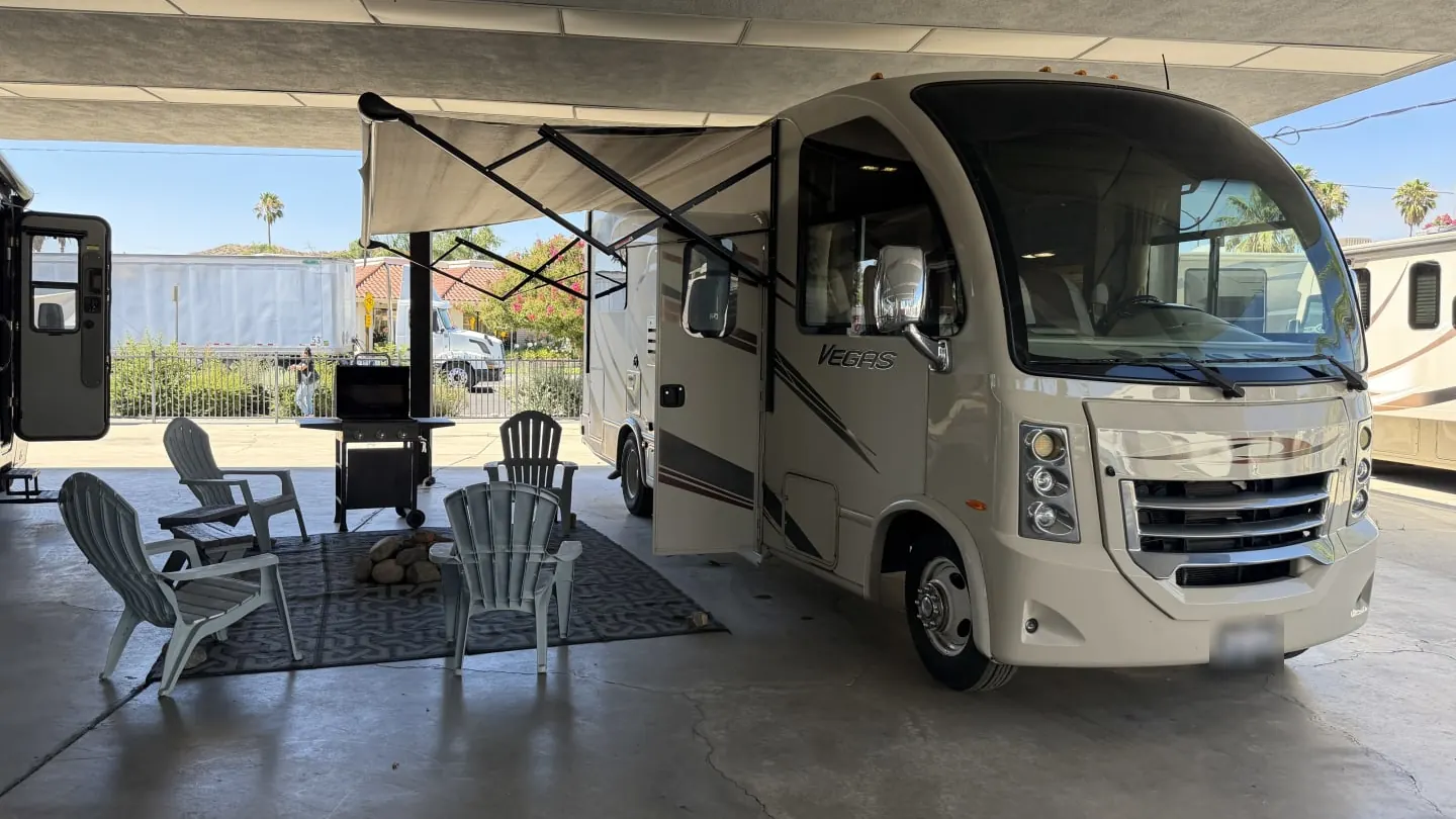 2015 Thor Vegas motorhome with its awning out and chairs set out under a canopy