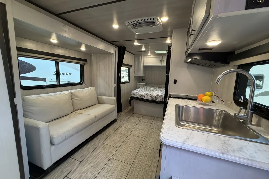 The sofa, galley and bedroom inside a 2023 Genesis Supreme Sea Breeze