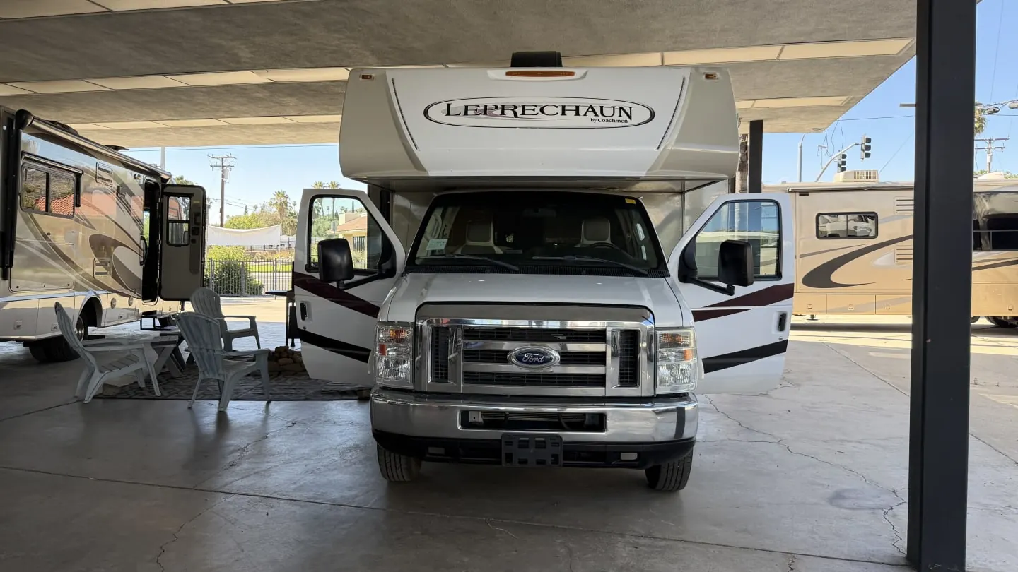 2018 Coachmen Leprechaun Class C motorhome with both cab doors open under a canopy