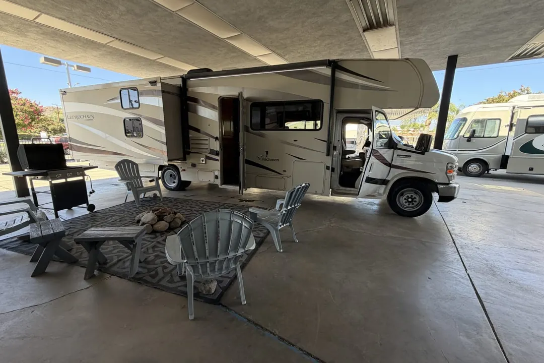 A 2018 Coachmen Leprechaun set up under a canopy with chairs and a grill
