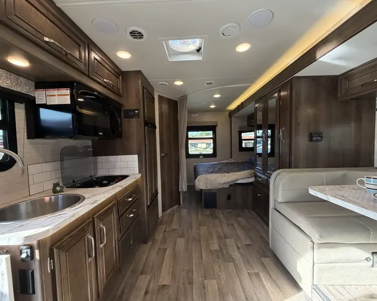 Galley, dinette and rear bed inside a 2021 Jayco Melbourne 24L Class C motorhome