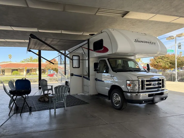 2019 Forest River Sunseeker 2650S Class C motorhome set up under a shade canopy with chairs and a grill