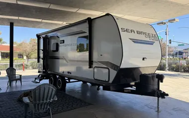 2023 Genesis Supreme Sea Breeze 19FSS travel trailer set up with chairs and a grill