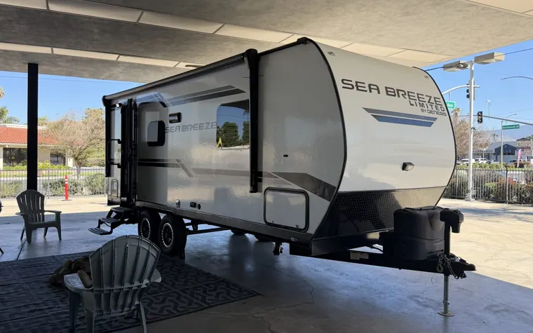 2023 Genesis Supreme Sea Breeze 19FSS travel trailer set up with chairs and a grill