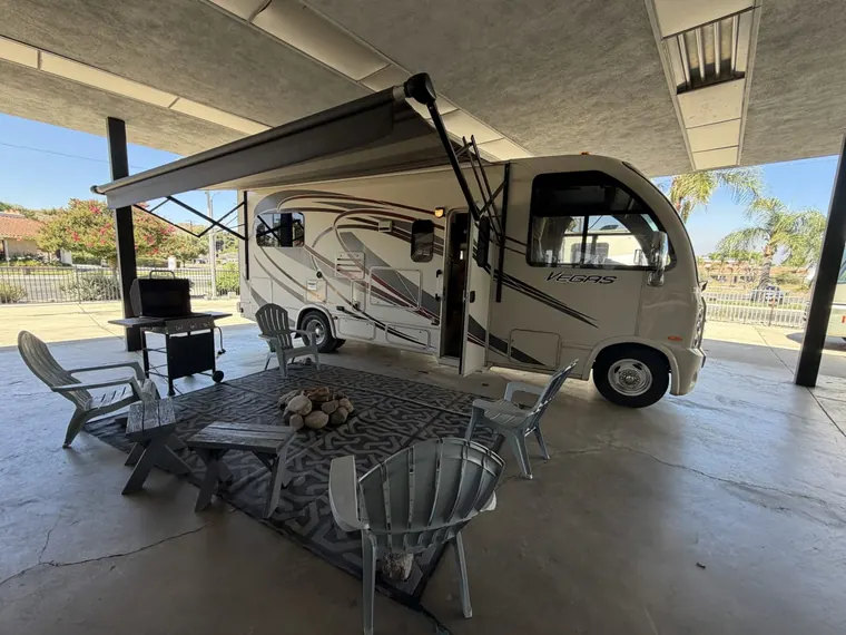 2015 Thor Vegas 24.1 motorhome set up for a renter with its awning out, chairs and a fire pit