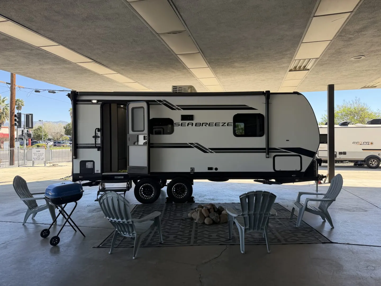 2023 Genesis Supreme Sea Breeze 19FSS travel trailer set up for a renter with chairs, a grill and a fire pit